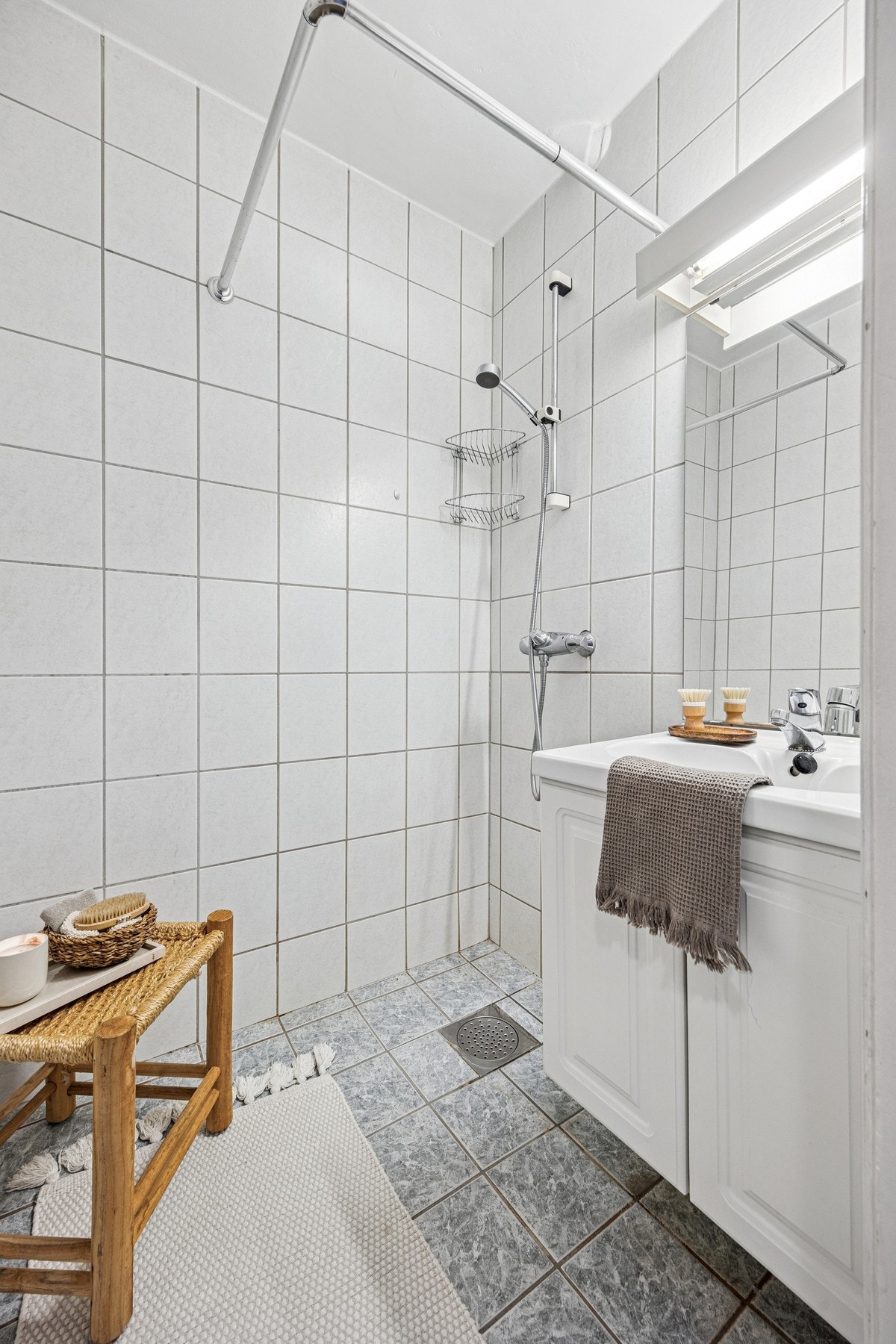 Badet på ca. 2 kvm er arealeffektivt utformet, med servant på hvitt underskap og åpen dusjløsning. Galleribilde