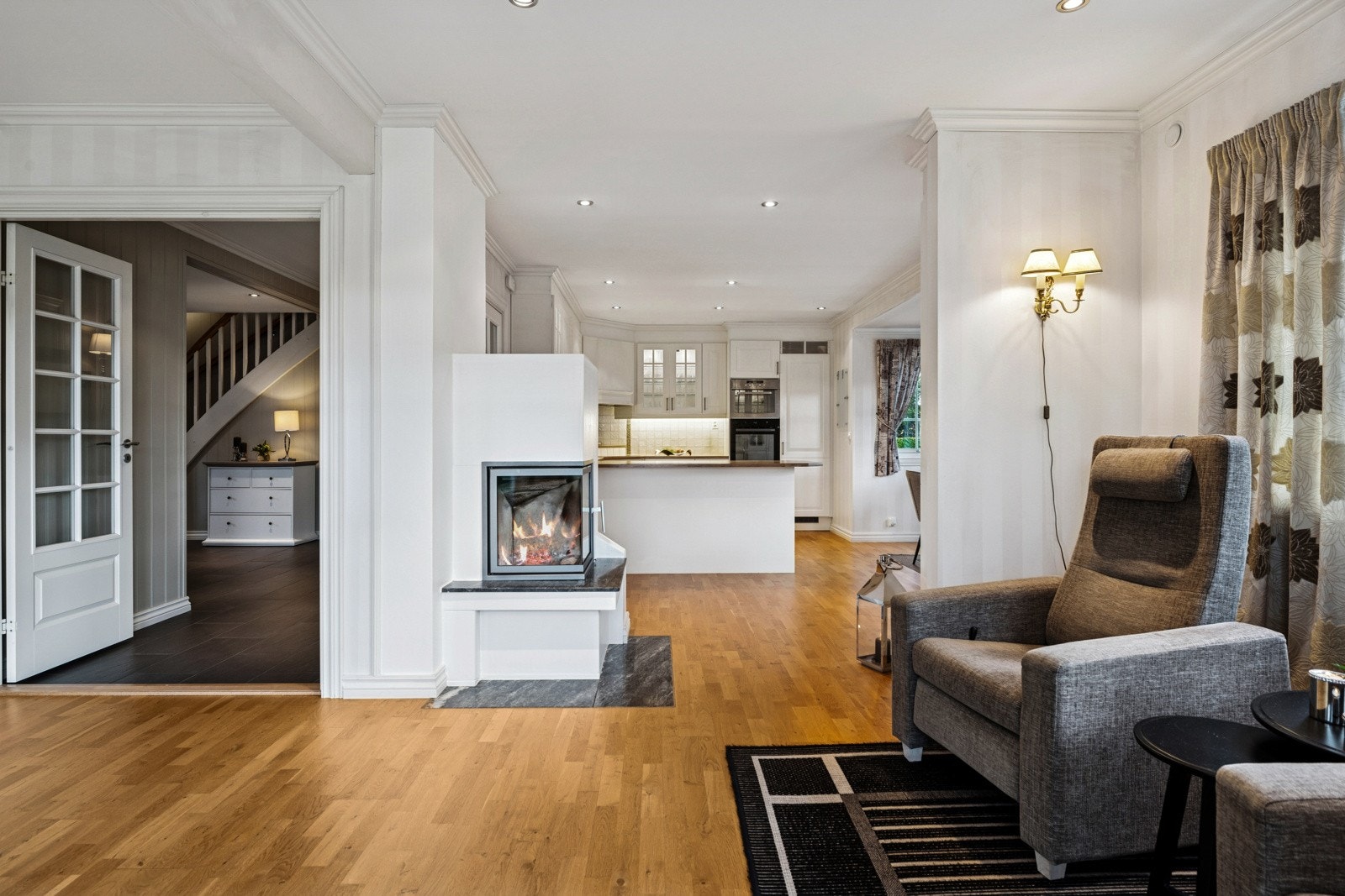 Åpen løsning mellom kjøkken og stue - med peis som skaper en lun atmosfære. Galleribilde