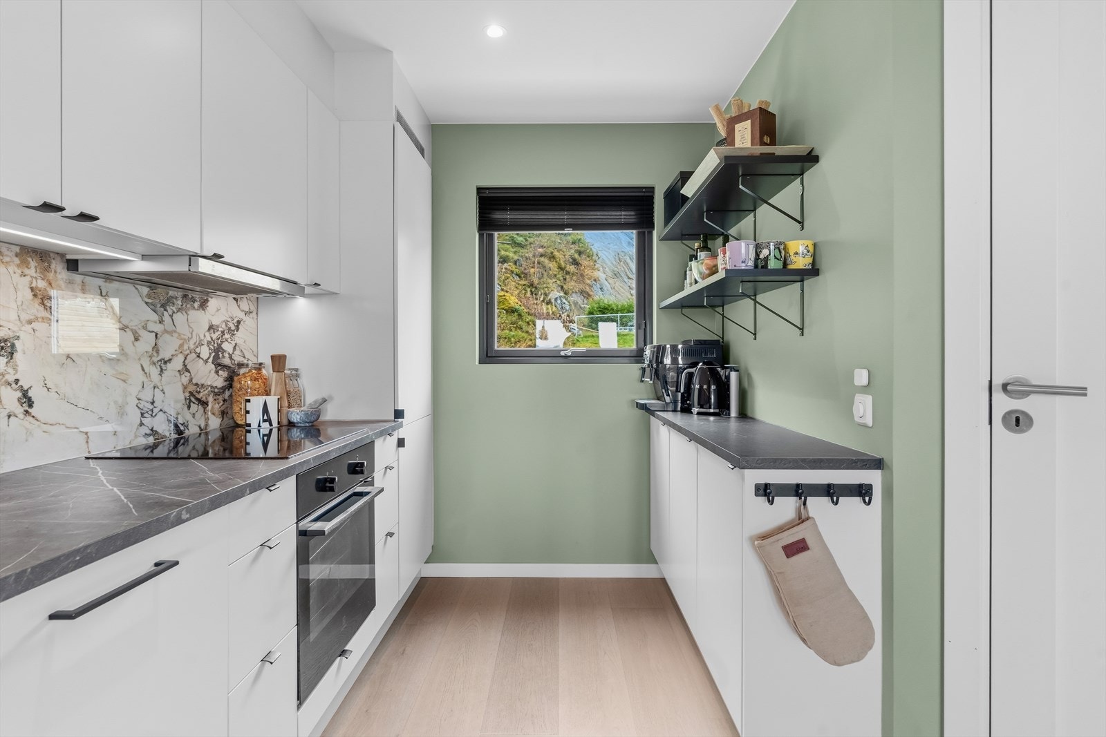 Mørk benkeplate med marmorisert mønster, og backsplash med marmoruttrykk som gir en fin brytning til det ellers stilrene. Galleribilde