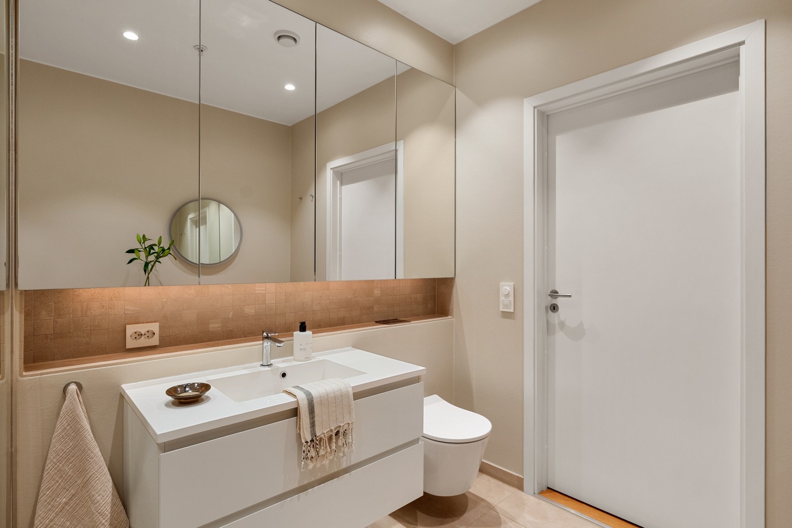 Øvrige vegger er glatte og lysmalte, foruten en flislagt hylle over servantinnredningen og toalettet, som er belagt med rustbrune fliser og belysning. Galleribilde