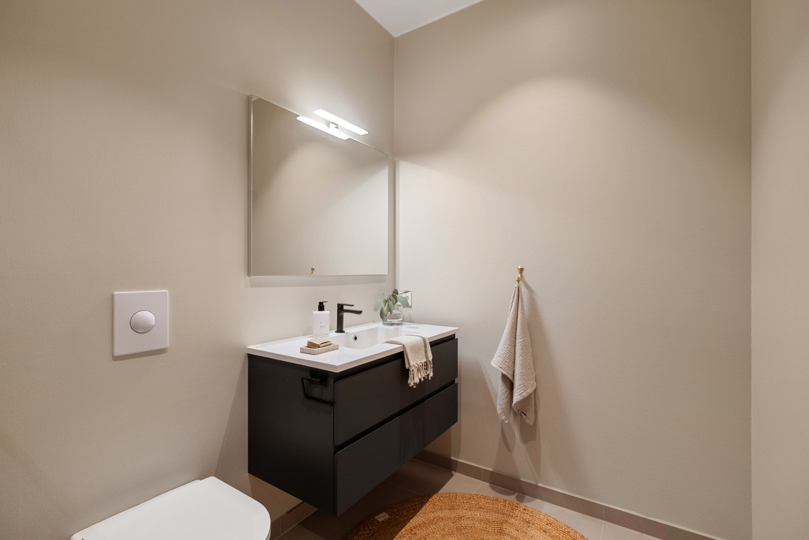 Gjestebadet har beige fliser på gulv med gulvvarme, flislagte vegger i dusjsonen og glatte, beigemalte vegger for øvrig. Galleribilde