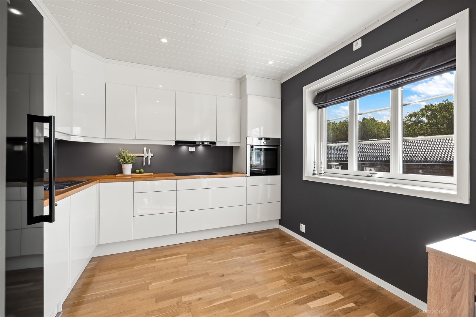 Klassisk og elegant kjøkkeninnredning med hvite slette høyglans fronter og benkeplate av eik. Galleribilde