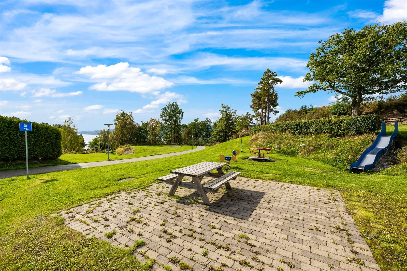 Felleseiet tomt. Eiendommen er opparbeidet med asfalterte gangveier, gressplen og beplantning. Galleribilde