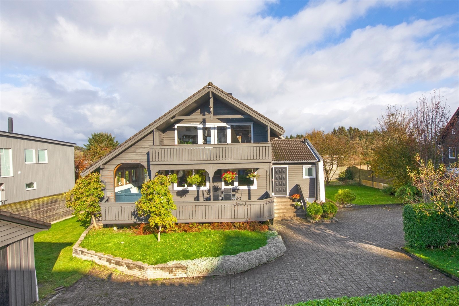 Stort solrikt uteområde opparbeidet med bla. terrasser, stor plen, prydbusker og frukttrær Galleribilde