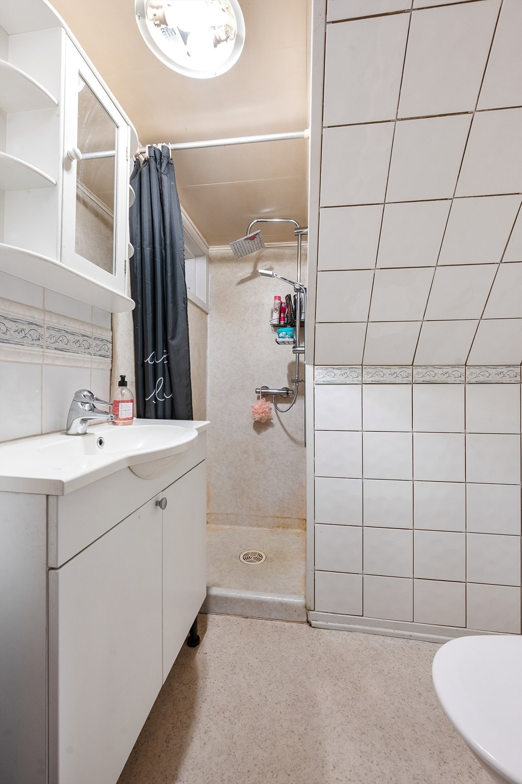 Bad i kjeller med praktisk dusjhjørne og servant med oppbevaring. Galleribilde