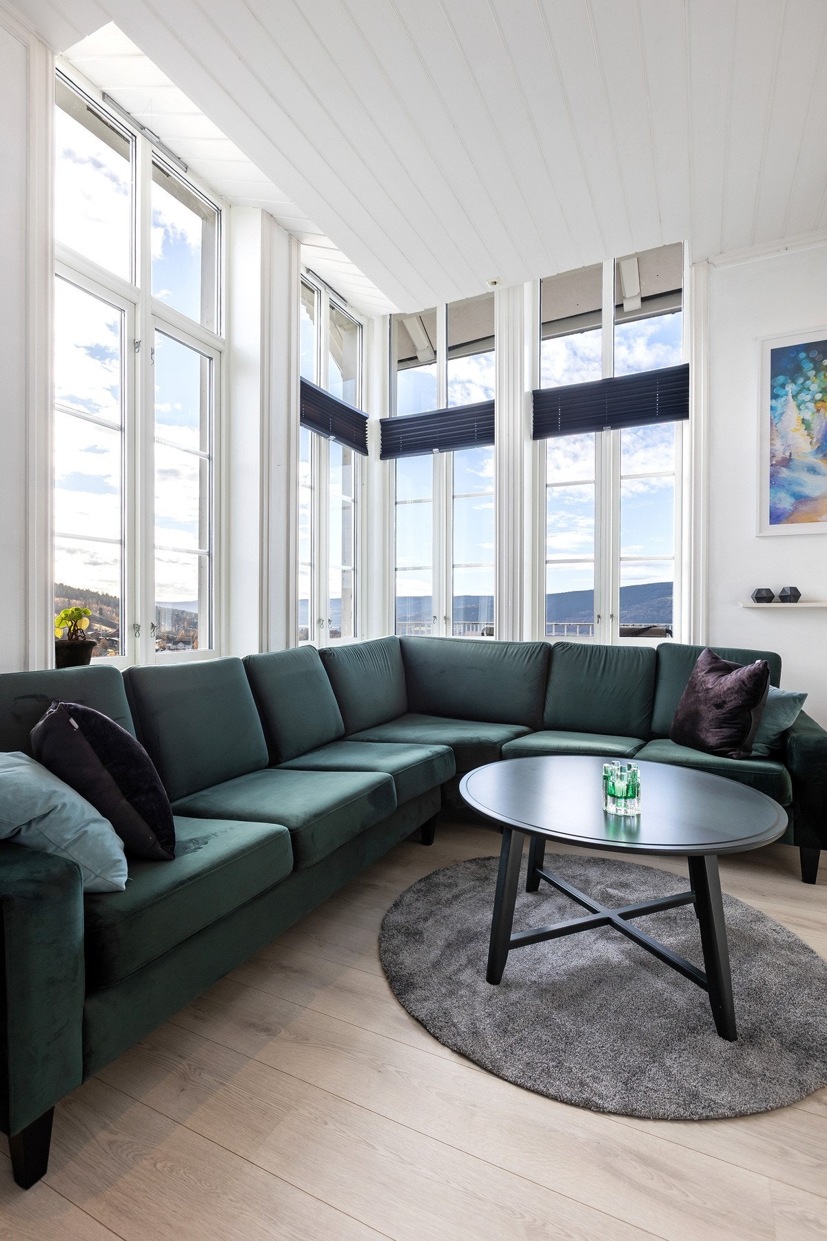 Trivelig sofakrok med store vinduer fra gulv til tak - perfekt for å nyte både dagslys og utsikten. Galleribilde