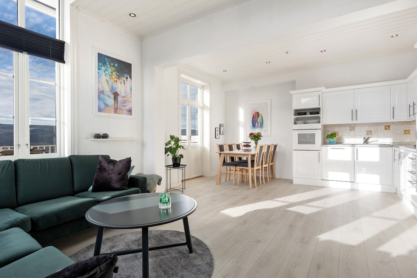 Stue og kjøkken i åpen løsning med plass for spisegruppe og sofagruppe i hver sin ende av rommet. Galleribilde