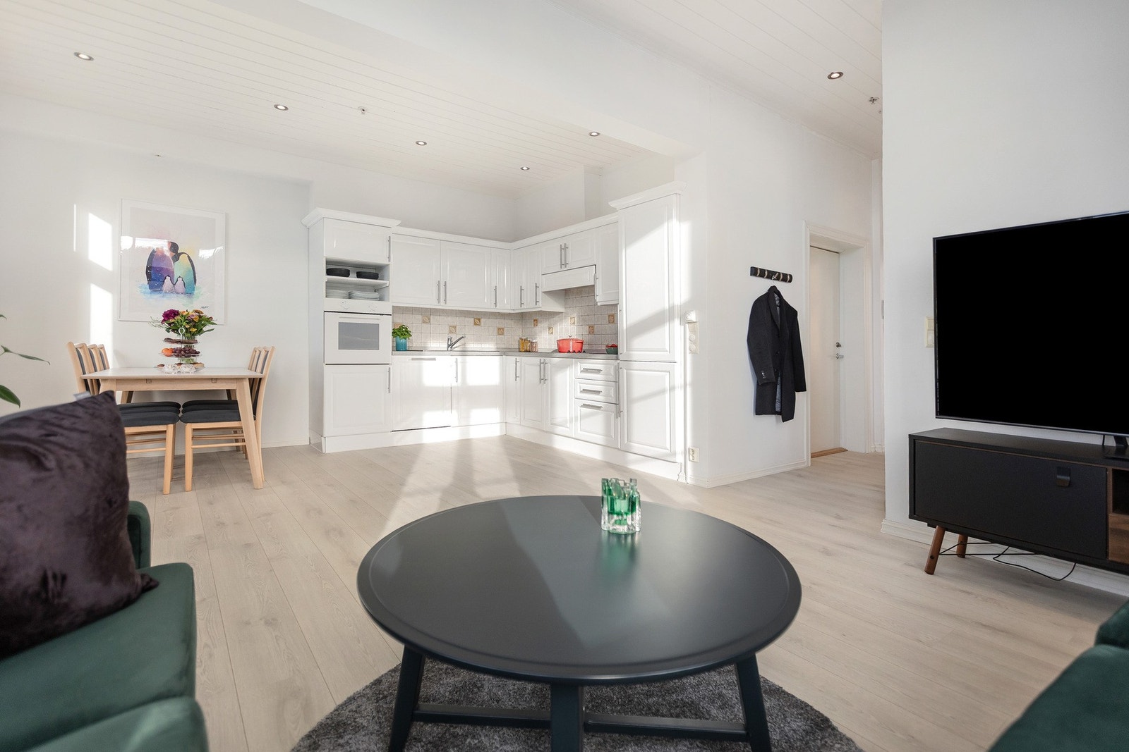 Åpen stue- og kjøkkenløsning med store vindusflater som slipper inn dagslys og skaper en luftig og hyggelig atmosfære. Galleribilde