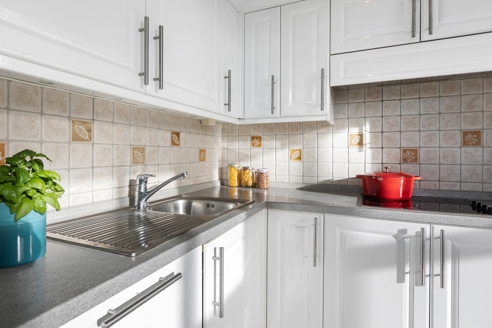 Praktisk kjøkkenløsning med fliser over benk, stilrene håndtak og gode oppbevaringsmuligheter. Galleribilde