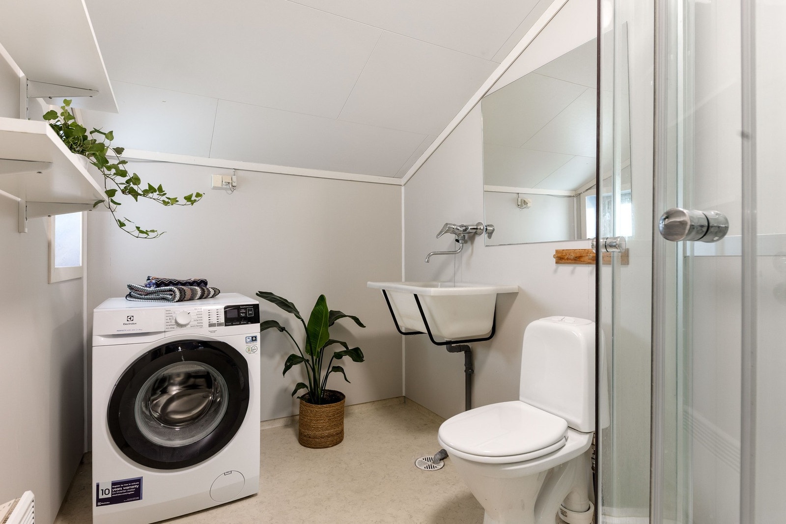 Bad/vaskerom i praktisk løsning med toalett, dusj og vaskekum og opplegg for vaskemaskin. Galleribilde