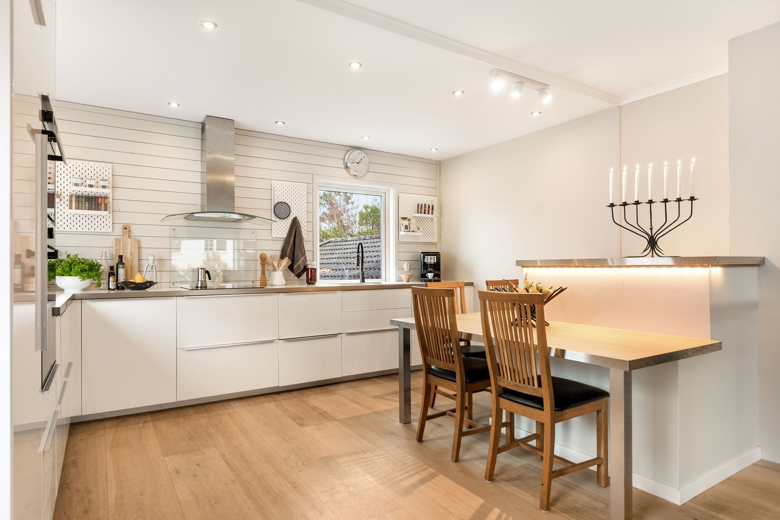 Lyst og moderne kjøkken i åpen løsning med integrert spisebord. Galleribilde