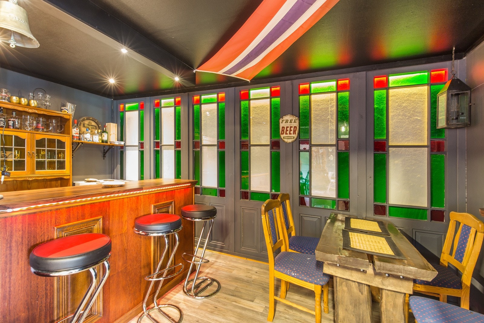 Innredet barområde med sitteplasser, bardisk og dekorative glassvinduer. Galleribilde