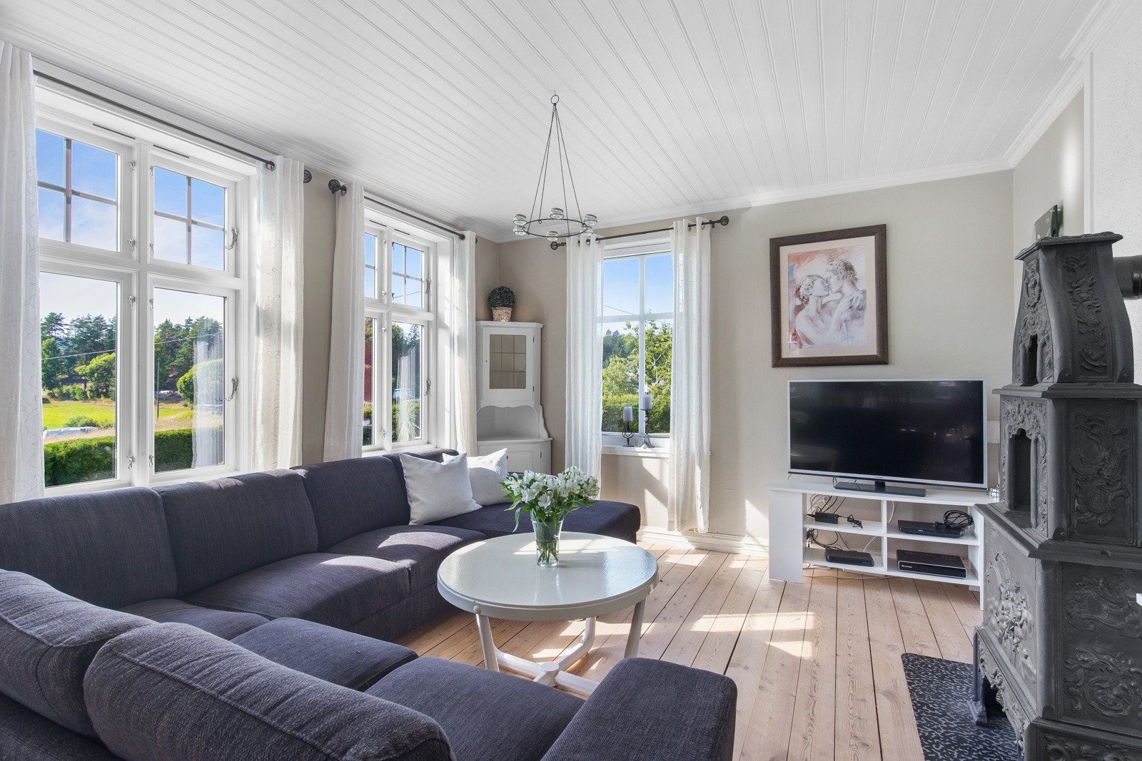 Lyst og romslig stueområde med store vinduer som slipper inn mye dagslys. Galleribilde