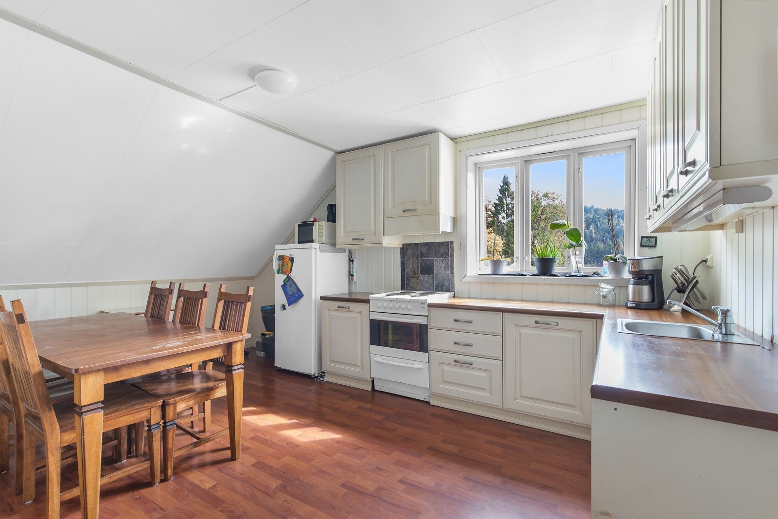 Kjøkken med spiseplass, god benkplass og naturlig lys fra vinduet. Galleribilde