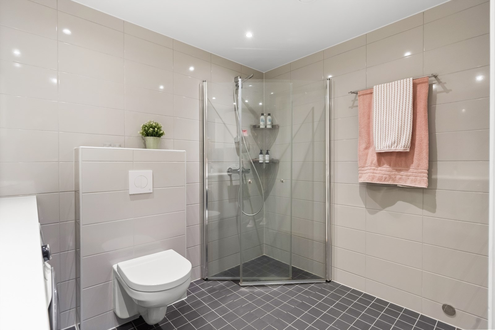 Badet er innredet med vegghengt klosett, servant nedfelt i benkeplate og dusjhjørne med svingbare glassdører. Opplegg for vaskemaskin. Balansert ventilasjon. Galleribilde