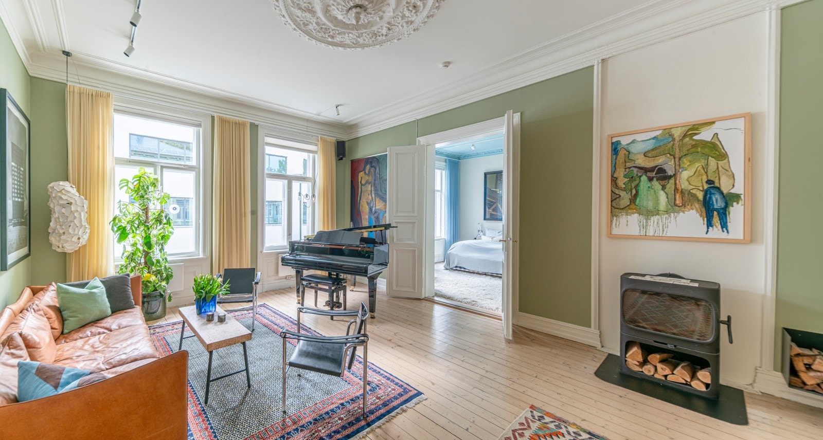 Lys stue med 28,4 kvm med ildsted og doble fløydører mot hovedsoverommet. Luftig takhøyde på 3,26 meter og med ildsted, sofagruppe og plass til flygel. Galleribilde