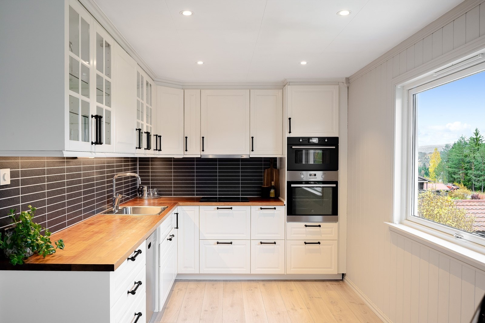 Pen kjøkkeninnredning med lyse profilerte fronter og laminert benkeplate med nedfelt oppvaskkum. Galleribilde