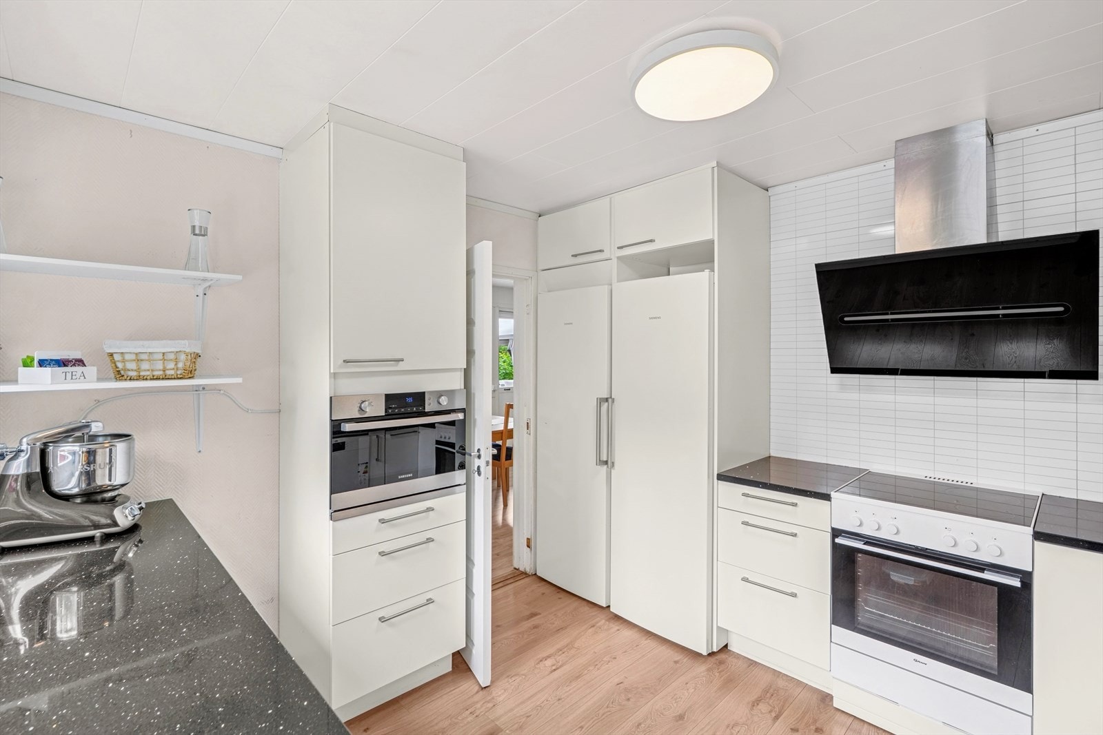 Kjøkkenet har hvitevarer i form av komfyr med keramisk platetopp, mikrobølgeoven, oppvaskmaskin, frittstående fryseskap og kjøleskap. Galleribilde