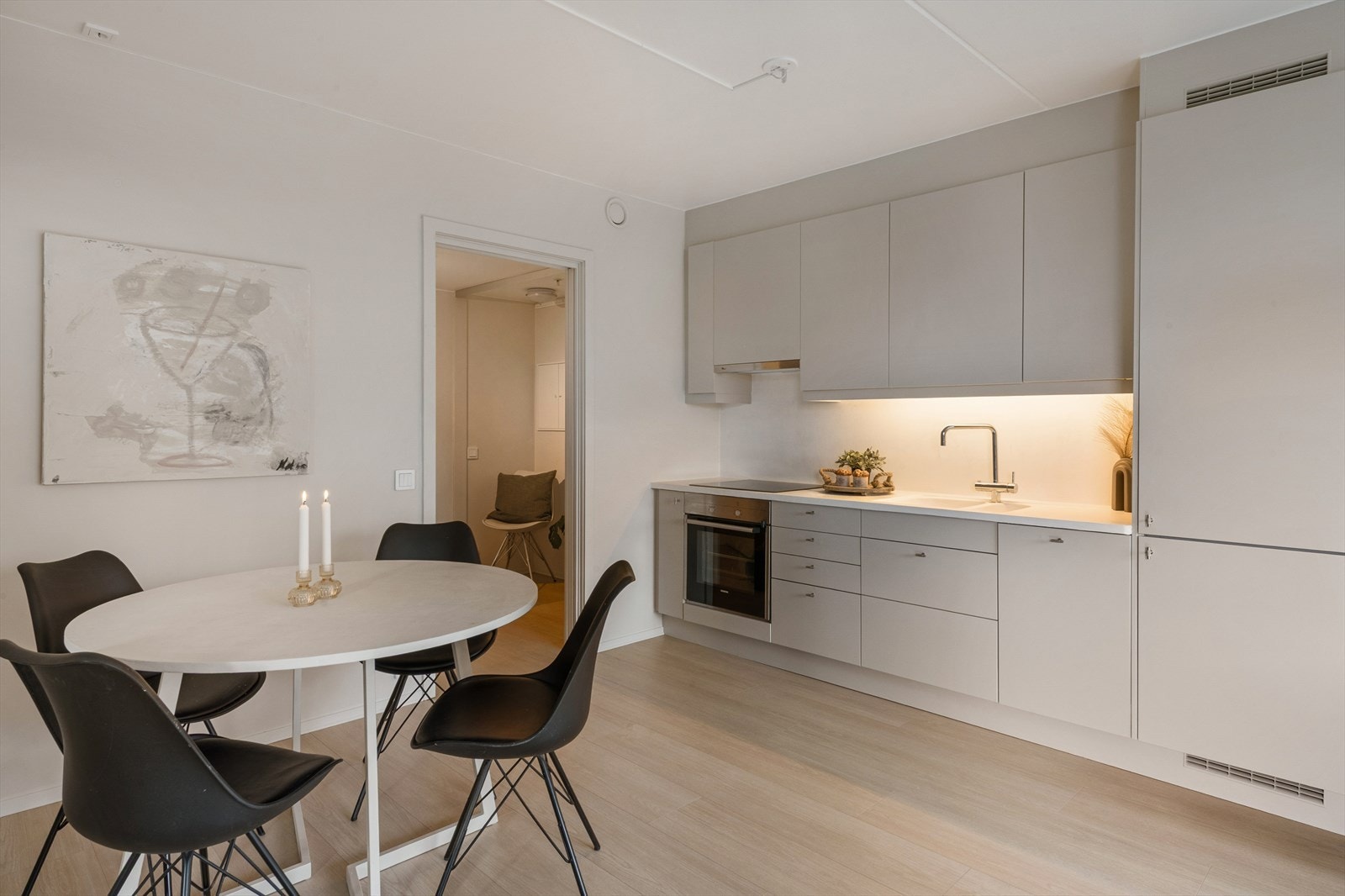 Kjøkkenet er fra byggeåret og levert av Marbodal. Det har glatte fronter, belysning under overskap, laminatbenkeplate med nedfelt stålkum og fliser over benken. Galleribilde