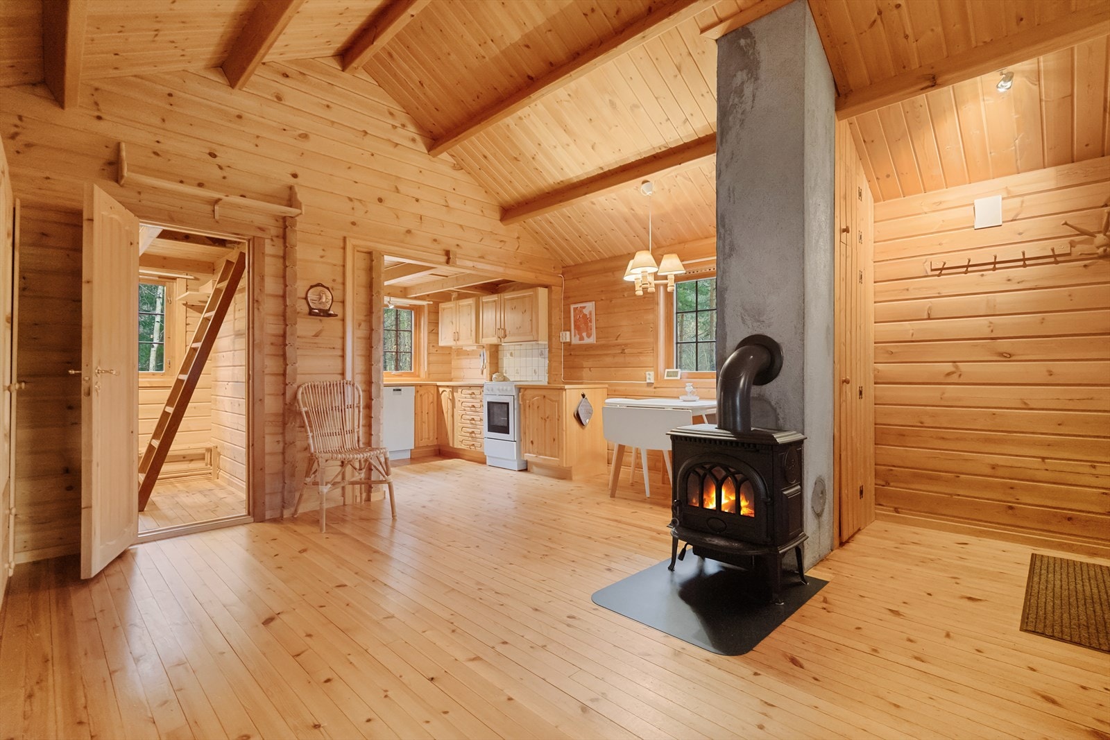 Lun og innbydende stue med synlige bjelker, panel i heltre og vedovn som gir varme og ekte hyttefølelse. Her er det rom for både ro og hyggelige kvelder foran peisen Galleribilde