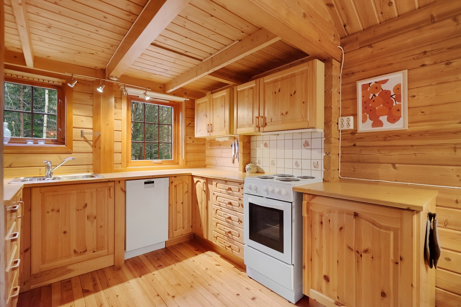 Koselig og funksjonelt kjøkken med rikelig skapplass og naturlig lys fra to vinduer. Et lyst og trivelig rom som inviterer til lange frokoster og kaffepauser med utsikt mot skogen Galleribilde