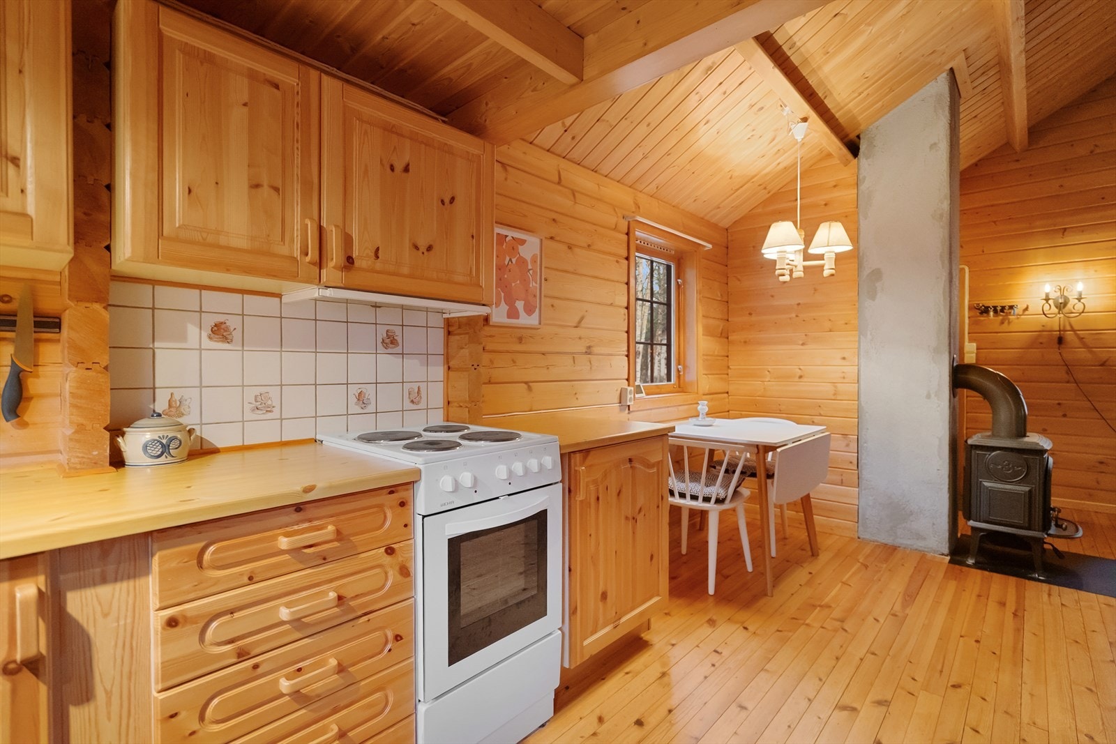 Her glir kjøkkenet sømløst over i spiseplassen og stuen, med vedovnen som et naturlig midtpunkt. En varm og innbydende atmosfære som passer like godt sommer som vinter Galleribilde