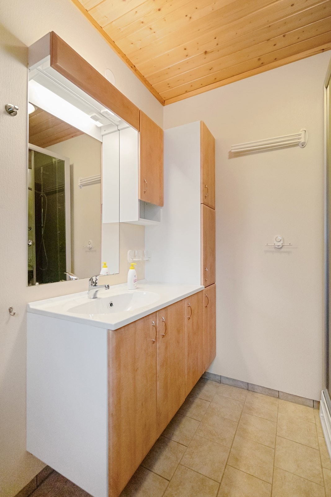 Romslig bad med lyse flater og varme i gulv. Her finner du både dusjkabinett, toalett og god oppbevaringsplass i innredningen Galleribilde