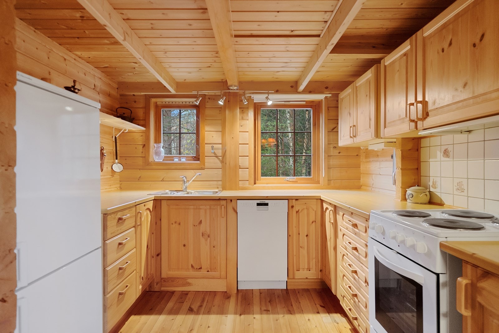 Klassisk hyttekjøkken i heltre med gode arbeidsflater og vinduer som slipper naturen inn. Kjøkkenet er praktisk utformet og har alt du trenger for komfortabel matlaging på hytta Galleribilde