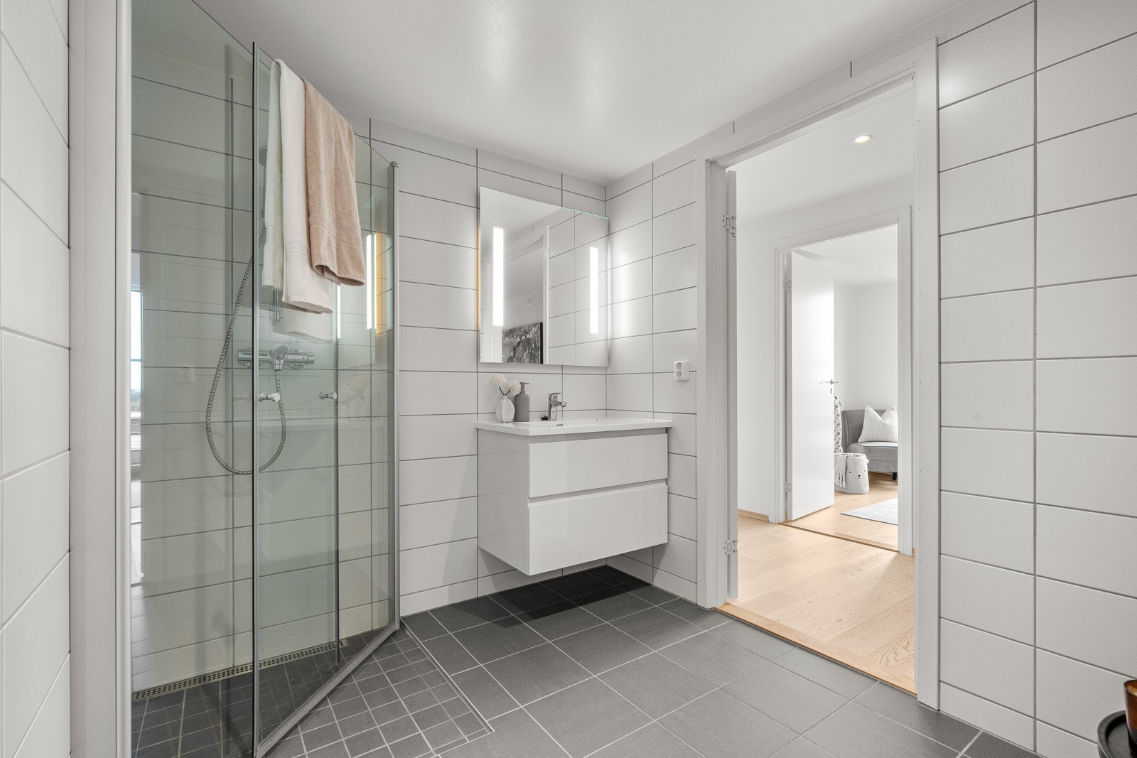 Videre utstyrt med dusjhjørne med innfellbare glassdører, vegghengt toalett og opplegg for vaskemaskin. Galleribilde