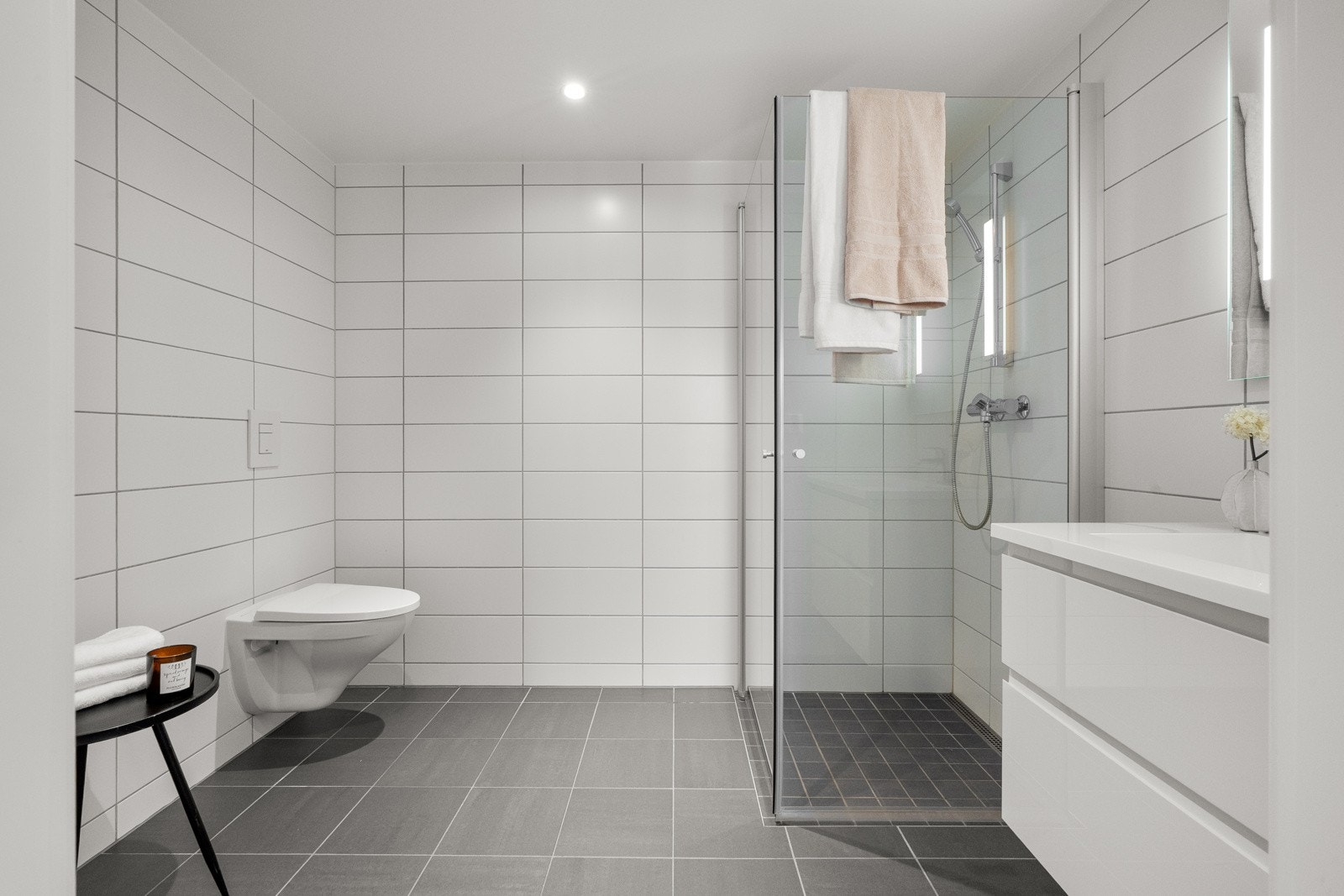 Baderommet med adkomst fra gangen har vegghengt servantinnredning med heldekkende servant, speil med lys og stikkontakt over servant. Galleribilde