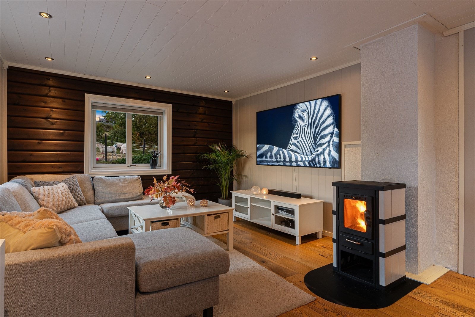 En vegg med malt tømmermannspanel gir rommet karakter og står i fin kontrast til den hvite himlingen med downlights og det flotte parkettgulvet med gulvvarme. Galleribilde