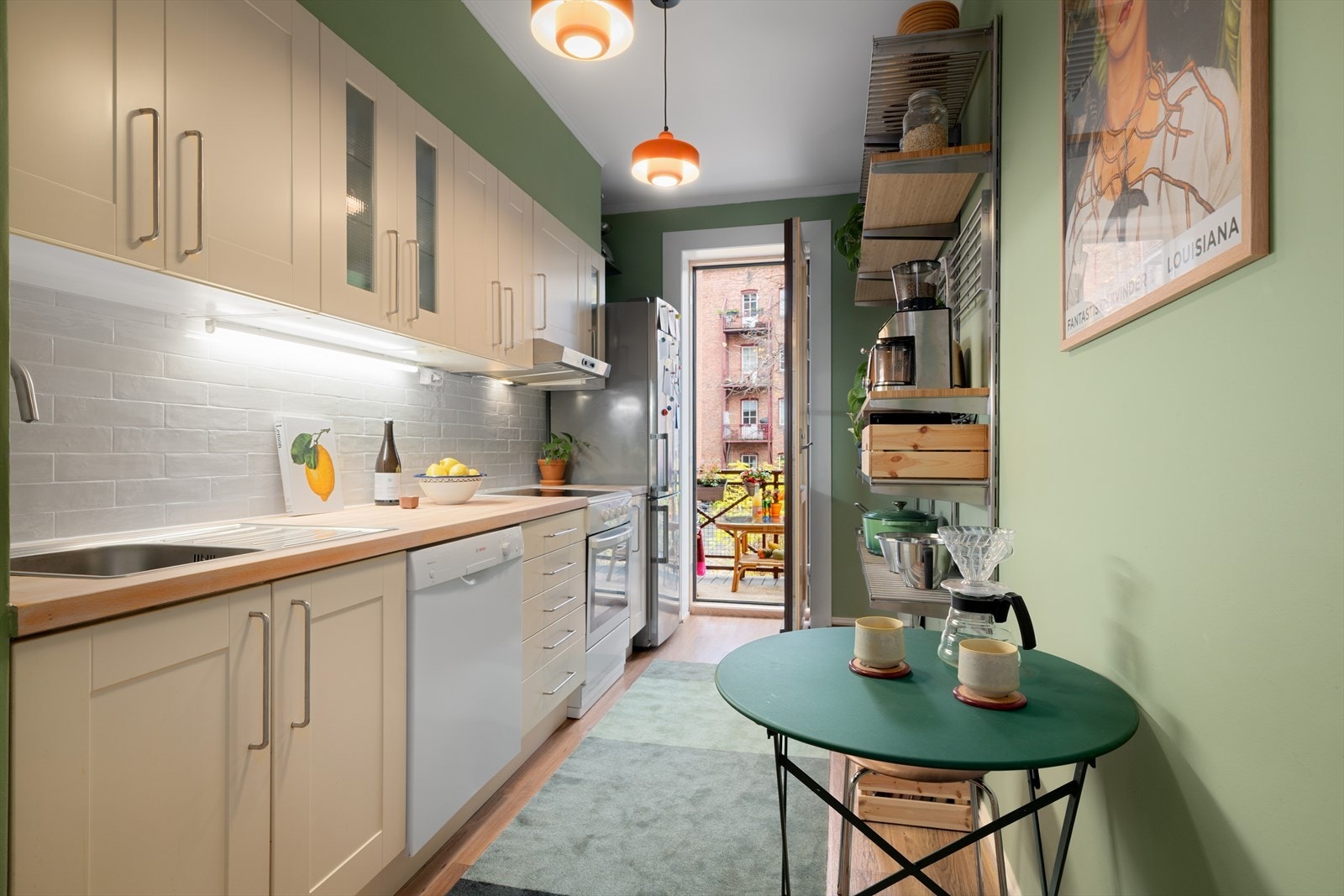Det separate kjøkkenet er malt i en dempet grønntone og gir deg en deilig følelse av sommer innendørs. Lyse, lettprofilerte fronter, samt to Vitrine fronter fra IKEA og heltre benkeplate. Fliser er montert på vegg over benk i 2025. Galleribilde