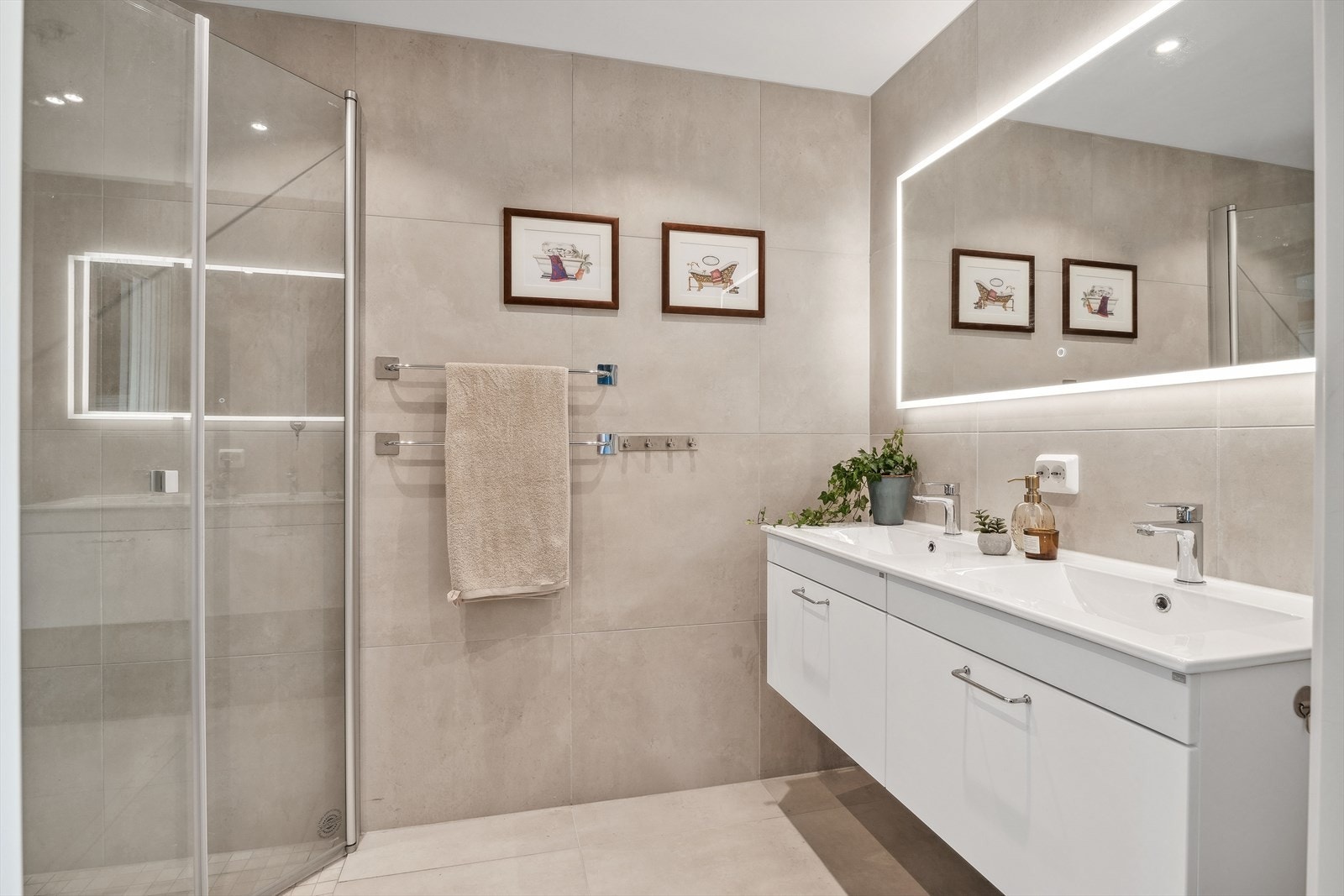 Flislagt og herlig en-suit bad med dusjhjørne, dobbel servant og veggmontert toalett. Galleribilde