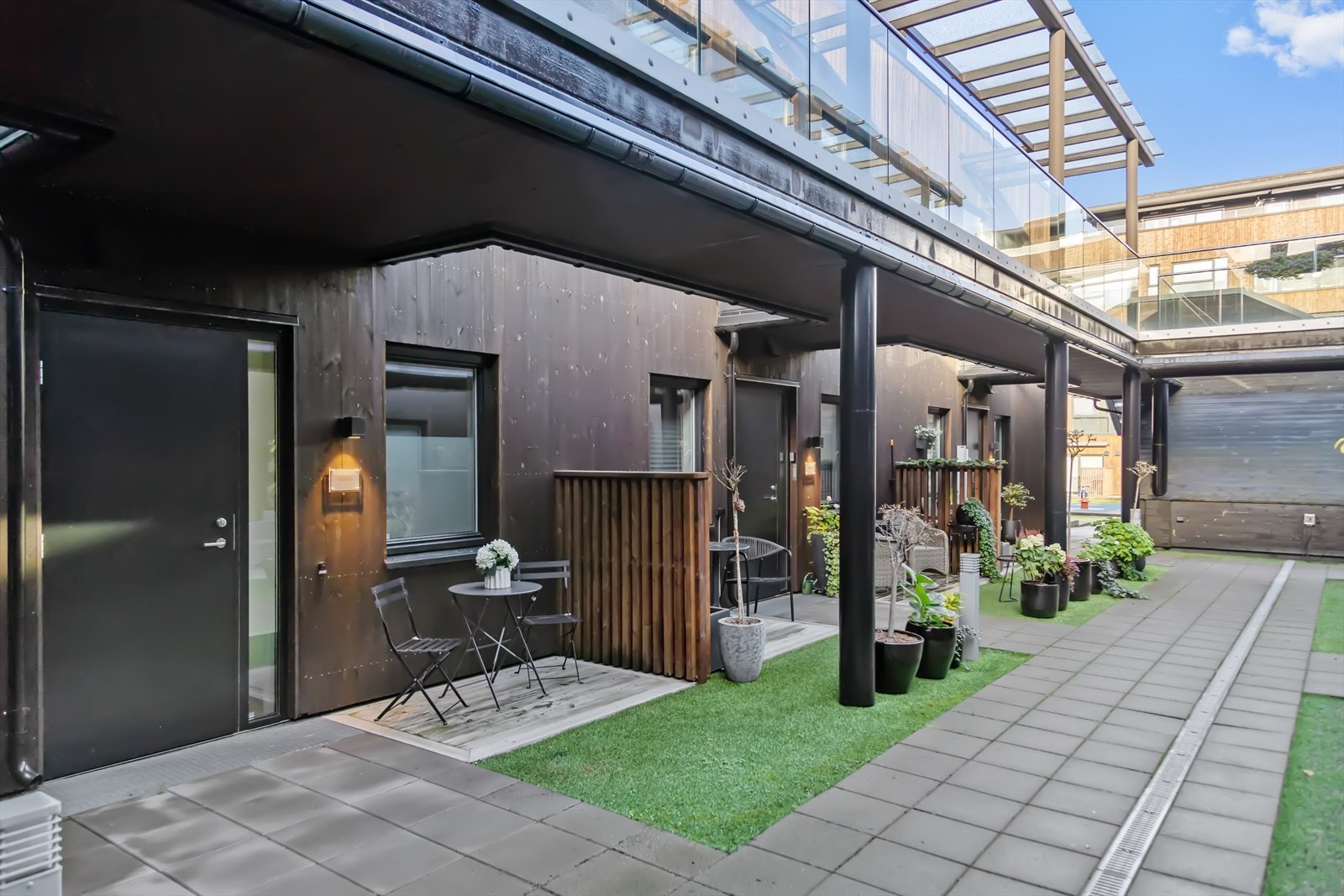 Ved inngangspartiet til leiligheten (på østsiden og ved fellesareal), er det en uteplass med tredekke hvor det er plass til utemøbler. Denne er blant annet godt skjermet av levegger/skjermingsvegger på begge sider. Galleribilde