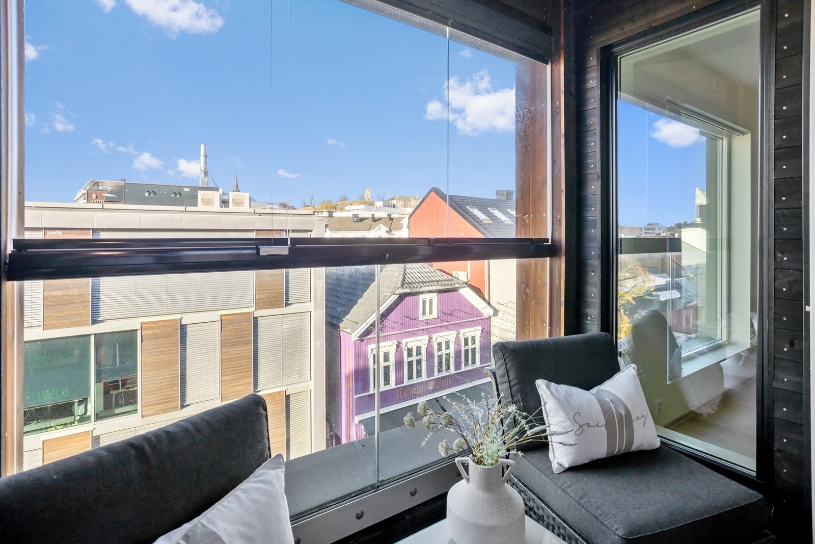 Terrassedekket er av impregnert tregulv, og det er stilfullt rekkverk av glass i enden av uteplassen. De lune treveggene på hver side i kombinasjon med tak over hele uteplassen skaper en intim og skjermet atmosfære. Galleribilde