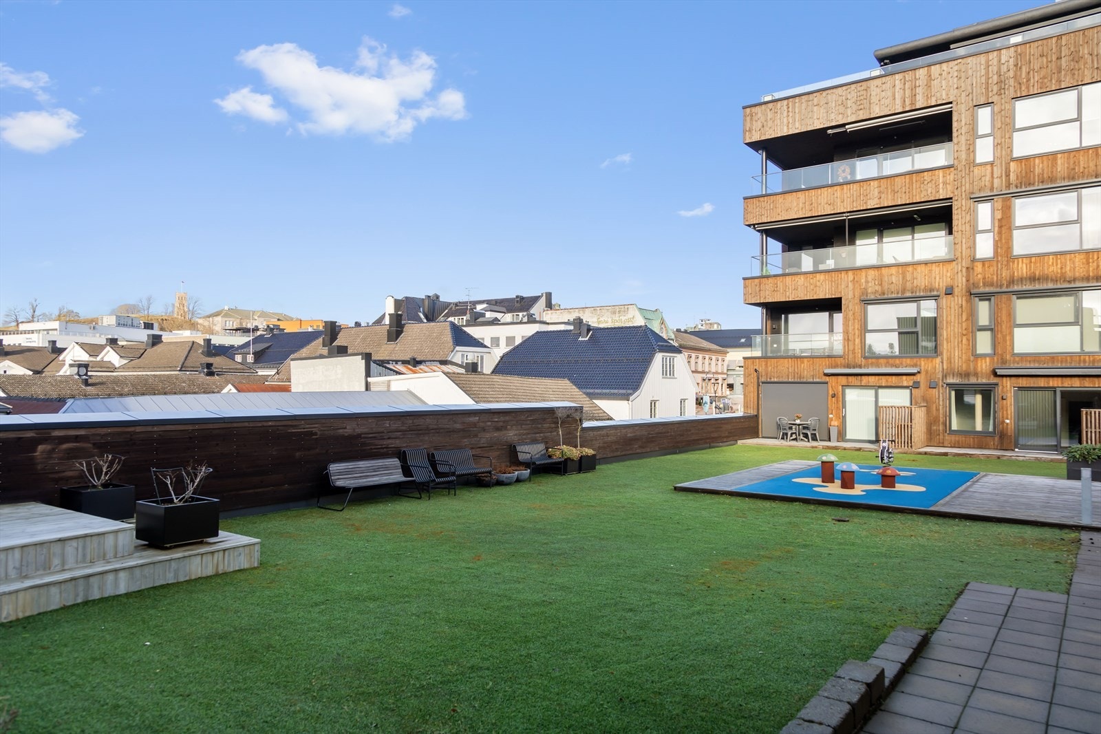 I atriumet, på samme plan som leiligheten, er det opparbeidet et eviggrønt område med kunstig gressplener med sittegrupper, lekeapparater med mer som er ment for hyggelig og sosialt samvær. Galleribilde