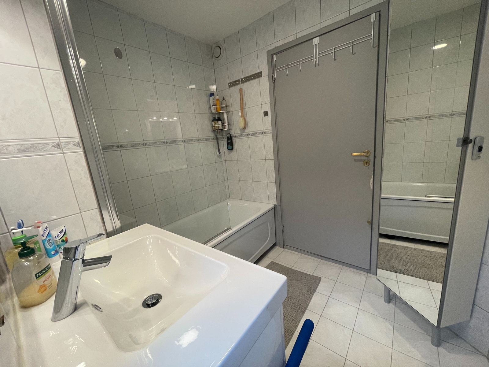 Flislagt bad utstyrt med speil, servant, toalett og badekar med dusj. Galleribilde