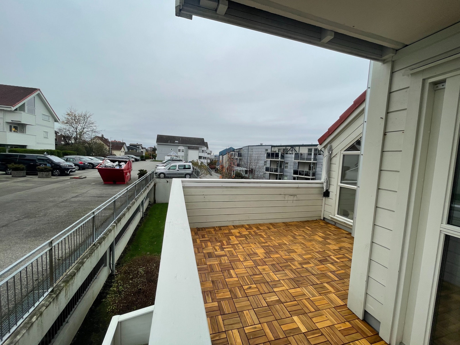 Balkong med kveldssol. Gjesteparkeringsområdet ligger svært nær leiligheten og er synlig fra balkongen. Galleribilde