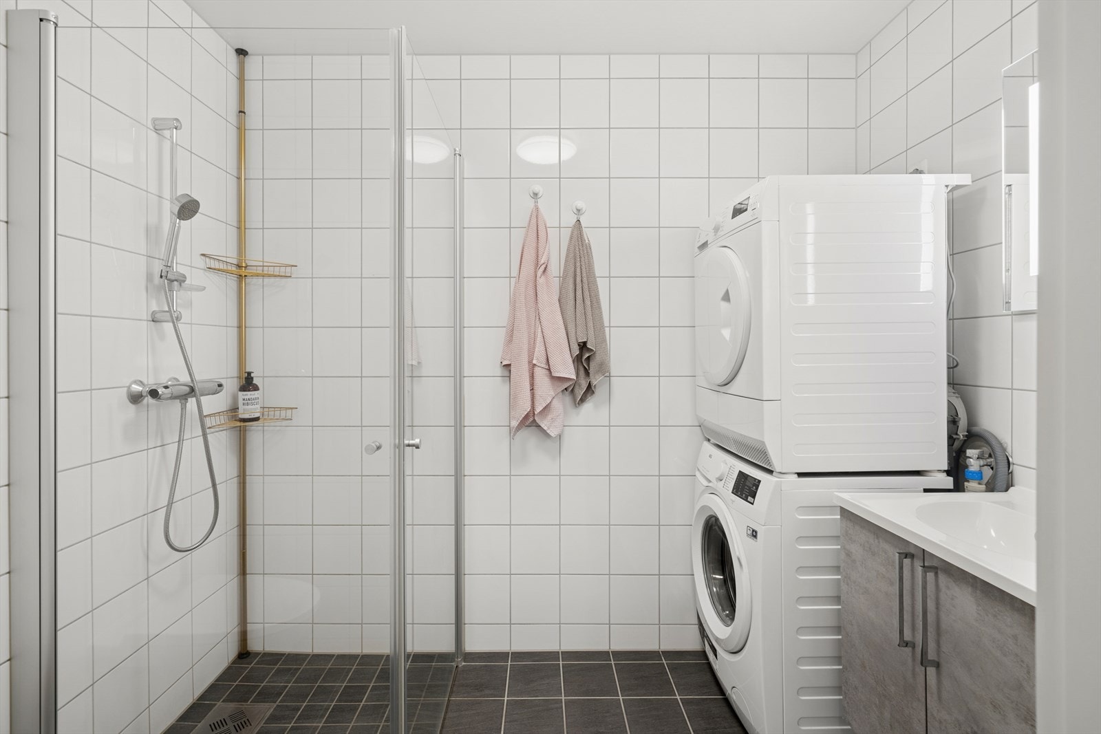 Baderommet er tidløst innredet med grå fliser på gulv og hvite fliser på vegg. I gulvet har man også vannbåren varme for ekstra komfort. Galleribilde