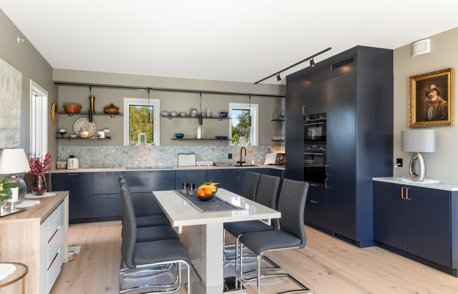 Innredningen har takhøye skap langs deler av den ene siden, mens endeveggen har en langstrakt benk med to vinduer, pendellamper og pene hyller over Galleribilde