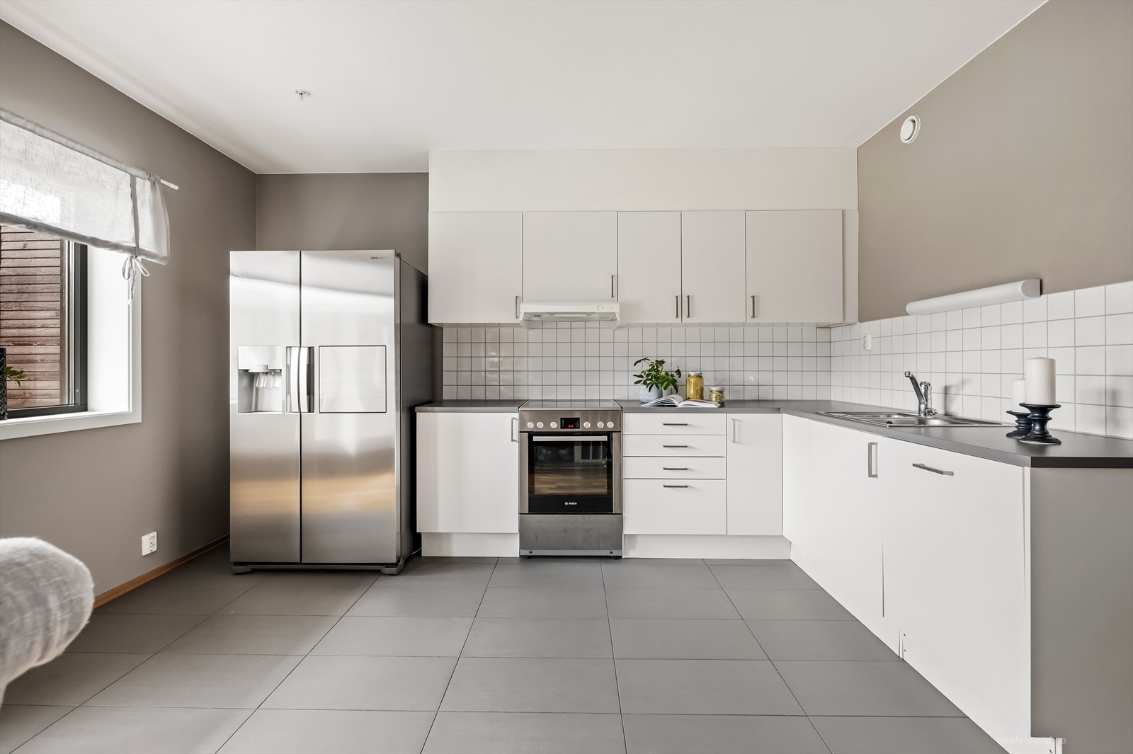 Stilrent og moderne kjøkken med hvitevarer og store vinduer som gir rikelig med dagslys. Galleribilde