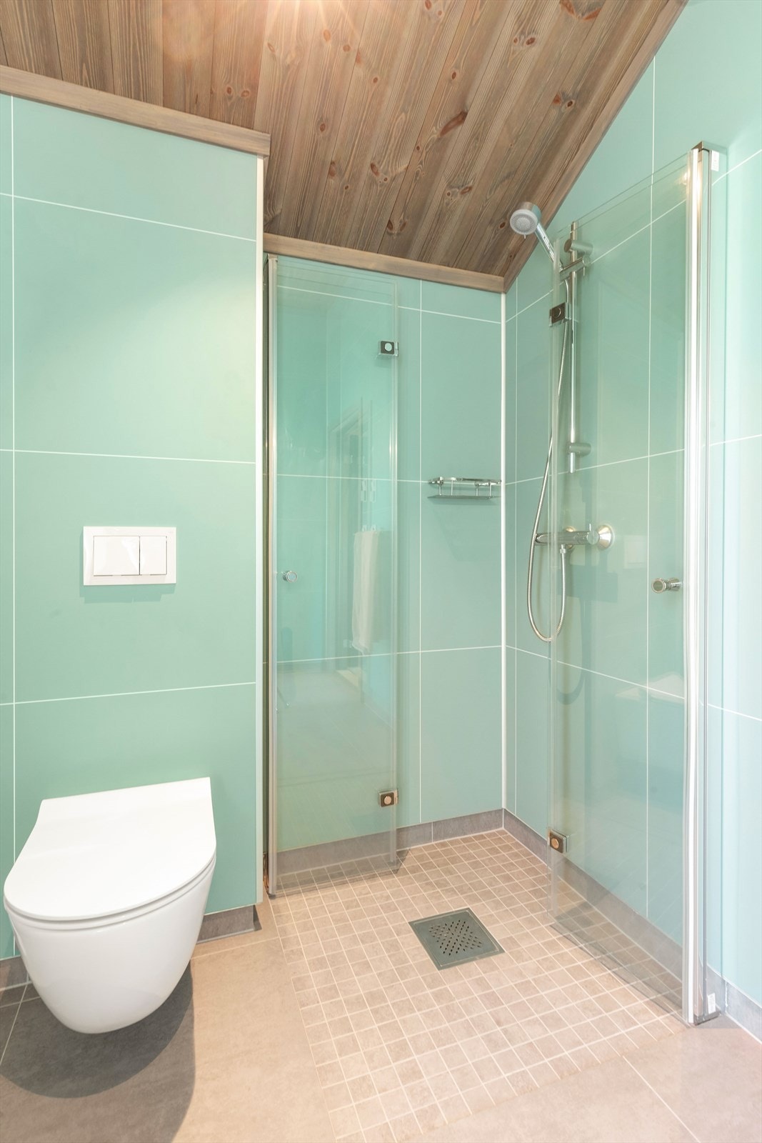 Vegghengt toalett, dusjhjørne og innredning med nedfelt servant. Galleribilde