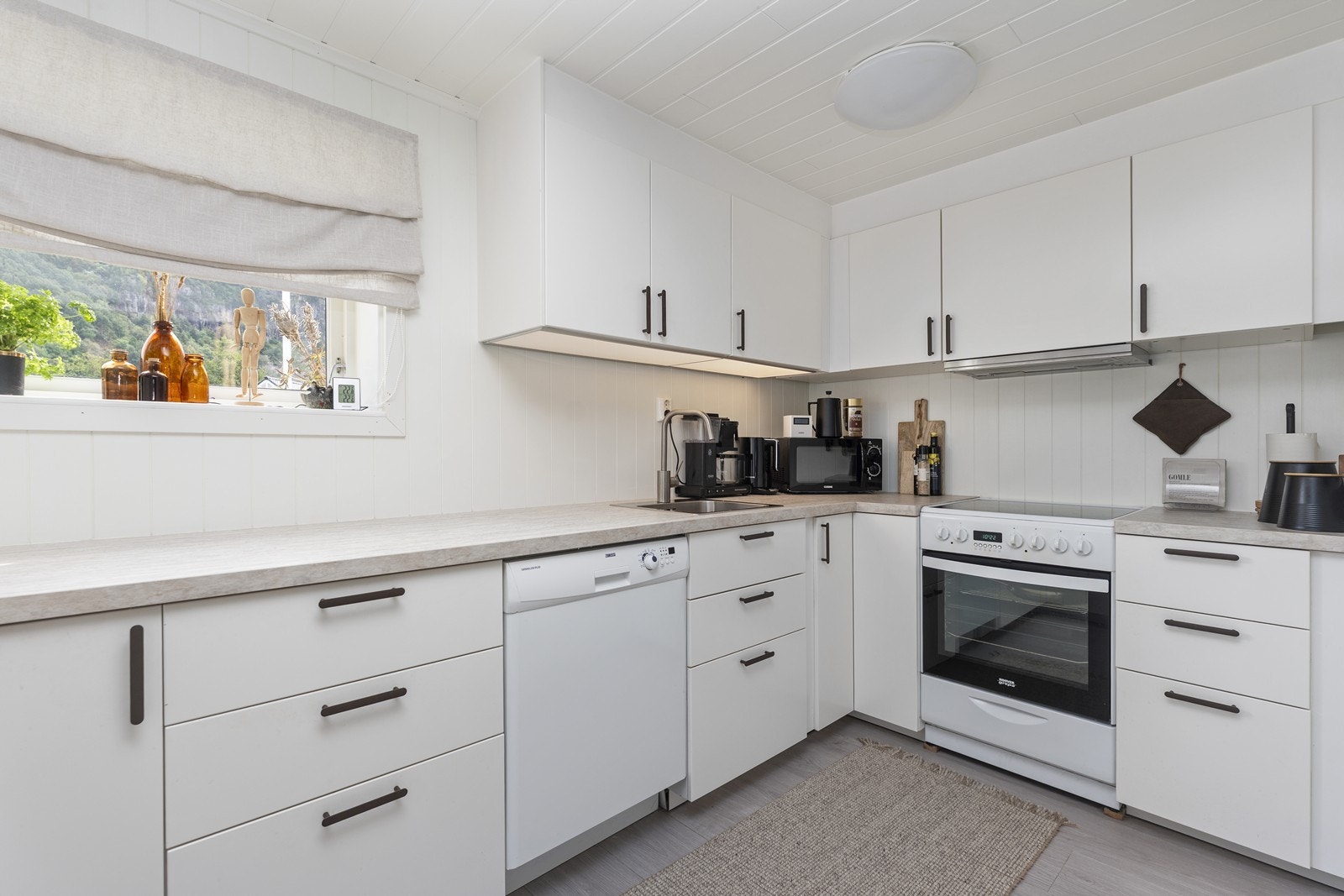 Kjøkkenet i underetasjen er tidløst med lyse overflater og lys benkeplate. God skap- og benkplass. Galleribilde