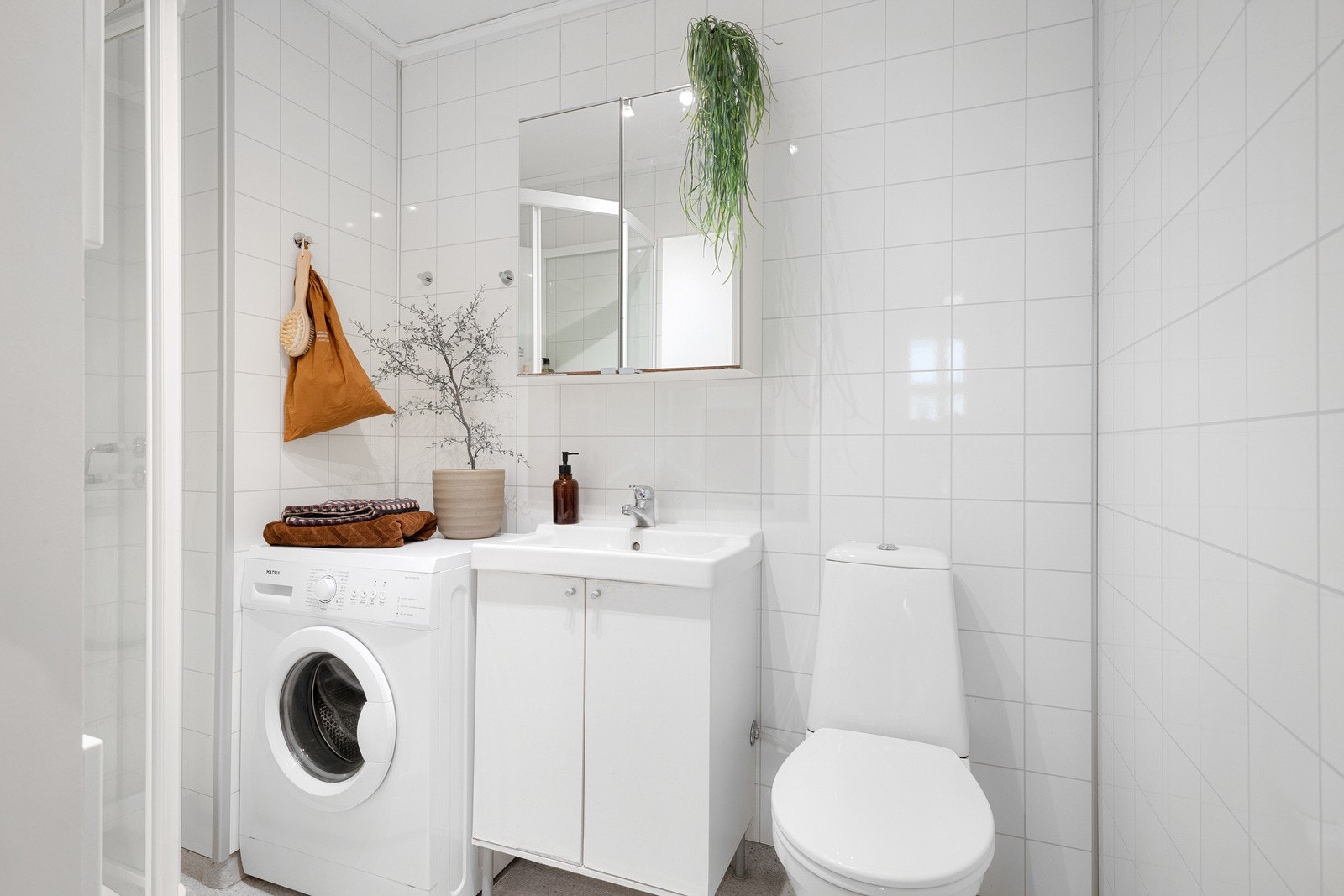 Baderommet har vegghengt servantinnredning med heldekkende servant, speilskap, dusjkabinett, gulvstående toalett og opplegg for vaskemaskin. Galleribilde