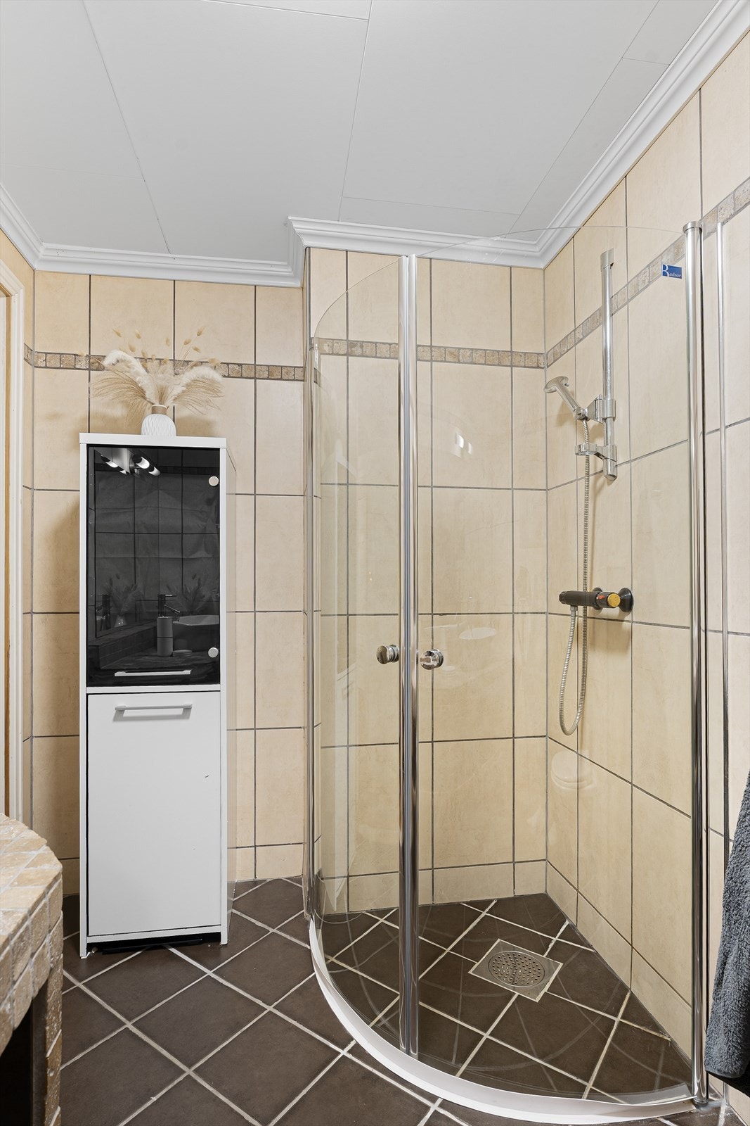 Badet har stedbygd innredning med servant, vegghengt toalett og stedbygd dusj med dusjdører Galleribilde