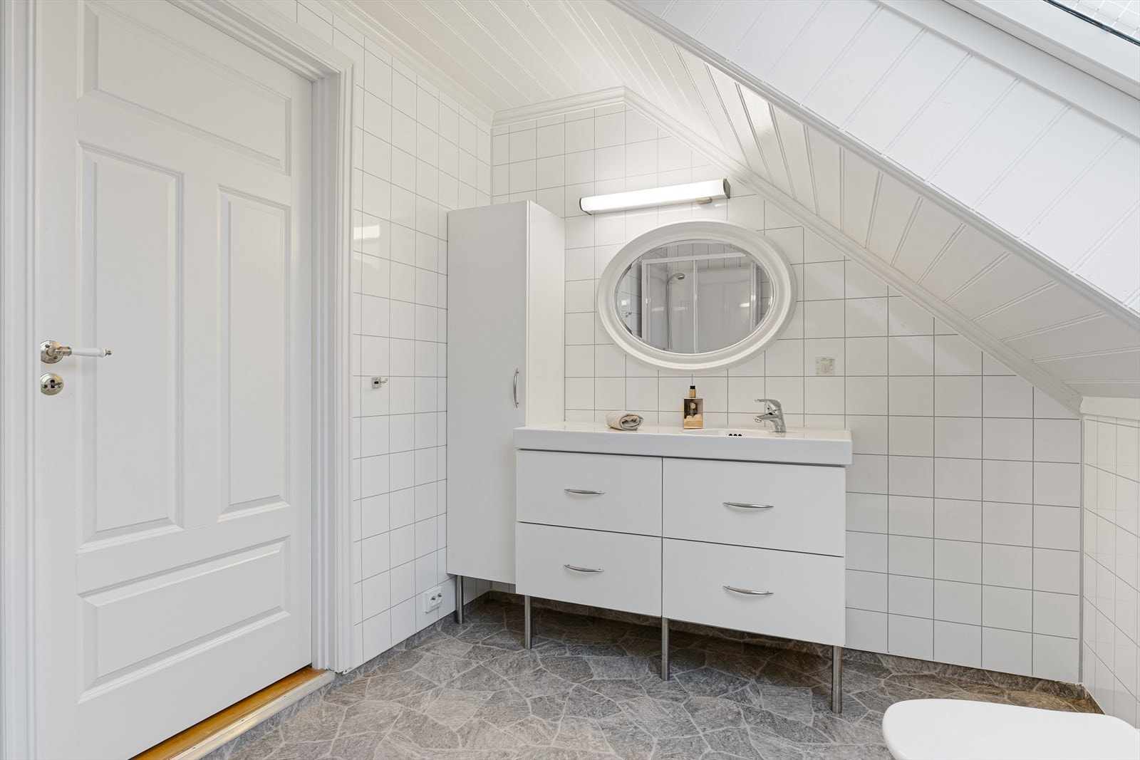 Badet på loftet har baderomsplater på vegger, vinylbelegg på gulv og malt panel i himling Galleribilde