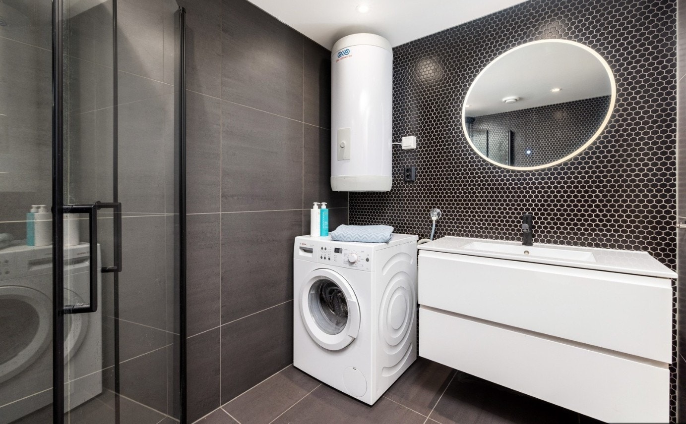 Flislagt bad med pen innredning og vaskemaskin. Galleribilde