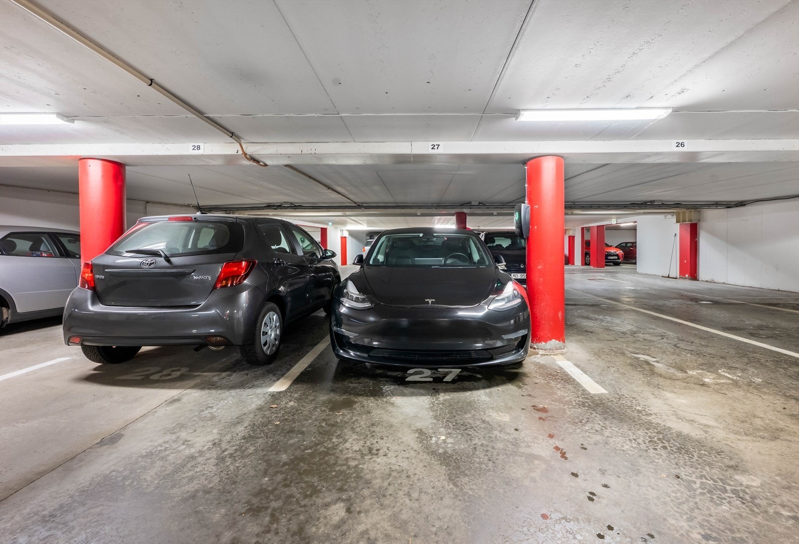 Garasjeplass nummer 27 er tilgjengelig i felles parkeringskjeller, med enkel tilgang via heis eller trapp. Plassen har lader for elbil. Galleribilde