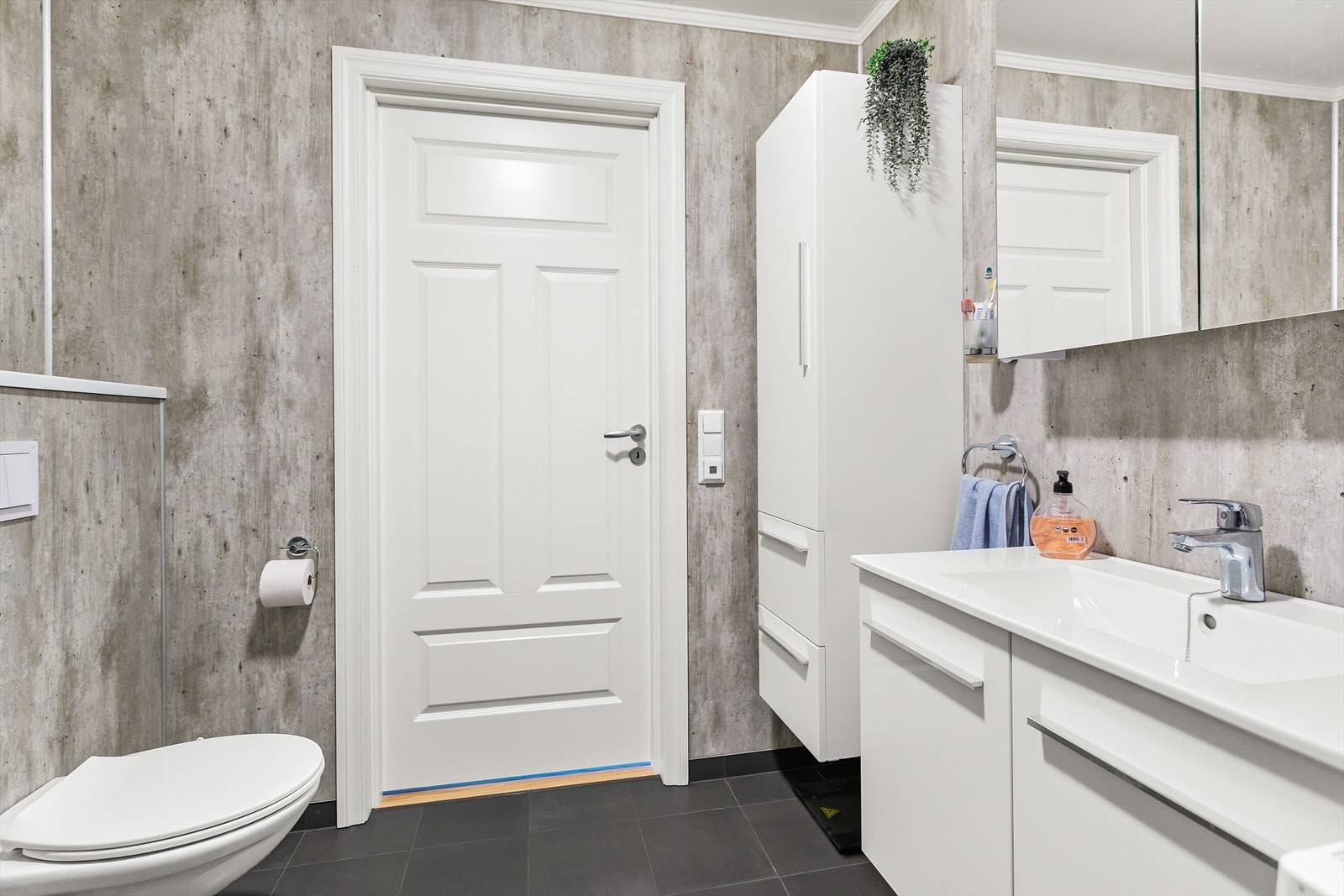 Badet er innredet med vegghengt toalett, servant i baderomsinnredning. vegghengt skap, speilskap og dusjhjørne. Galleribilde