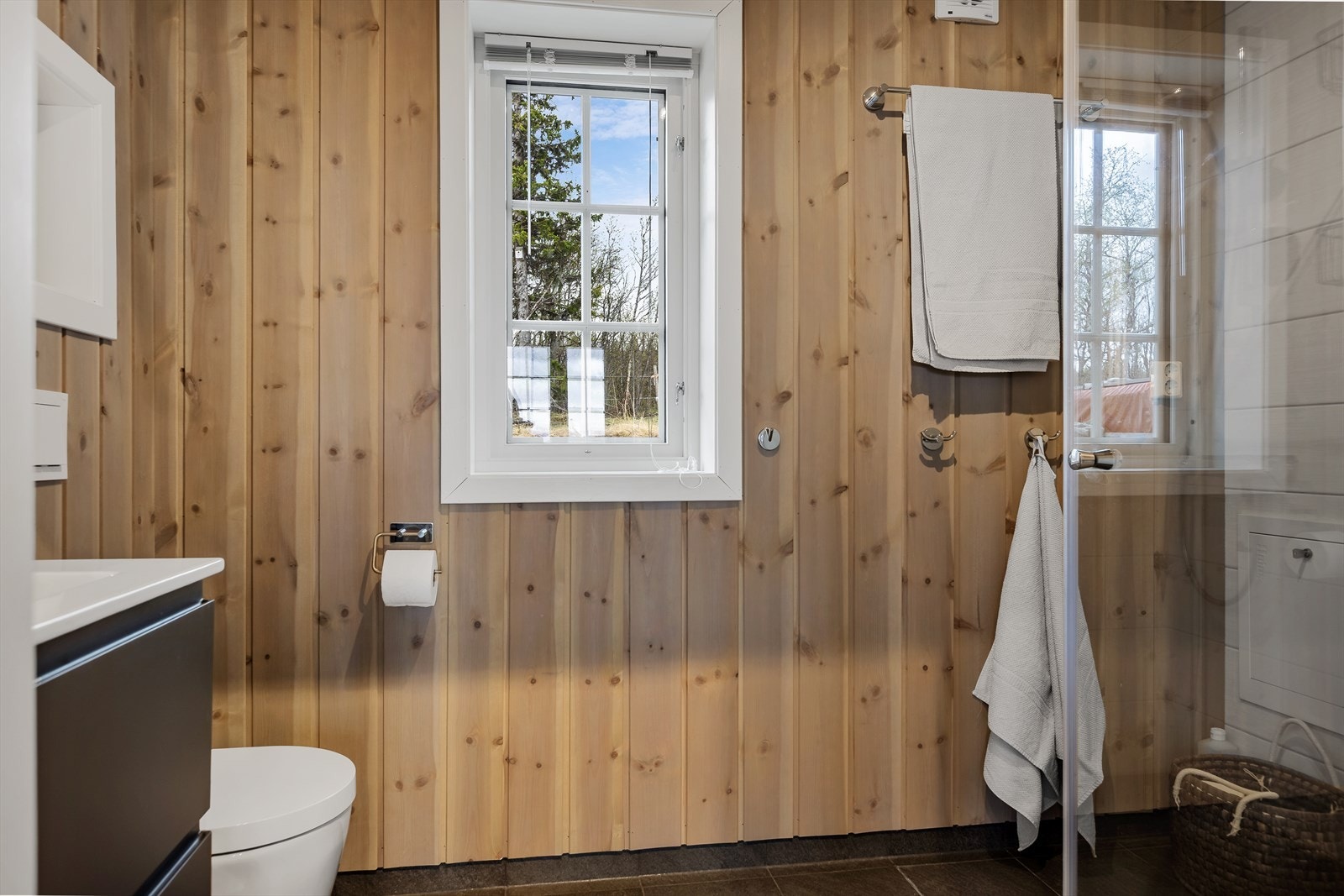 Bad/vaskerom har servant, vegghengt klosett, opplegg til vaskemaskin og dusj med glassvegger. Galleribilde